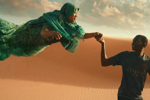 In der Wüste: Mann hält schwebende Frau an der Hand